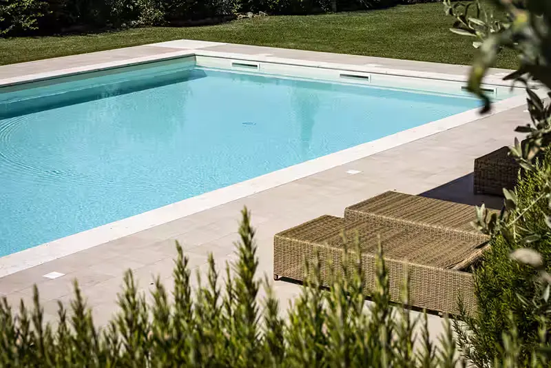 Dettaglio del bordo in pietra chiara di una piscina interrata realizzata da Lunipool
